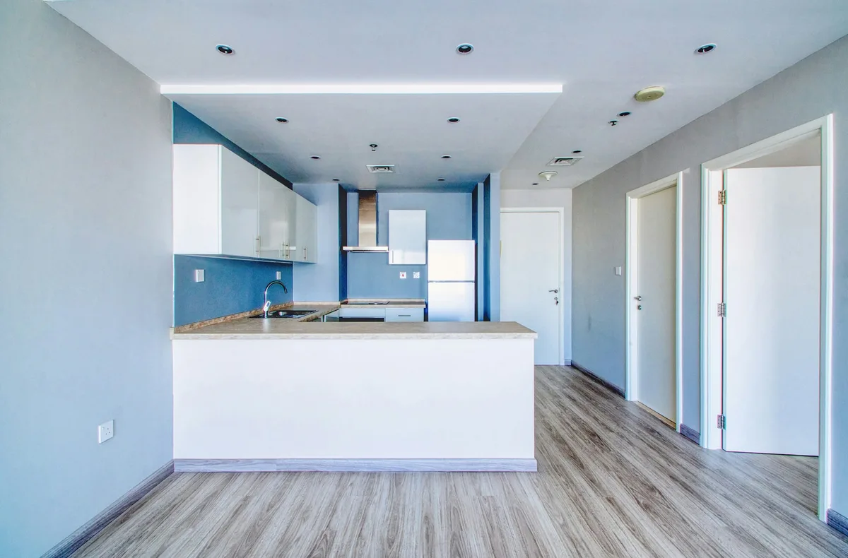 An unfurnished apartment with an open kitchen and adjoining rooms