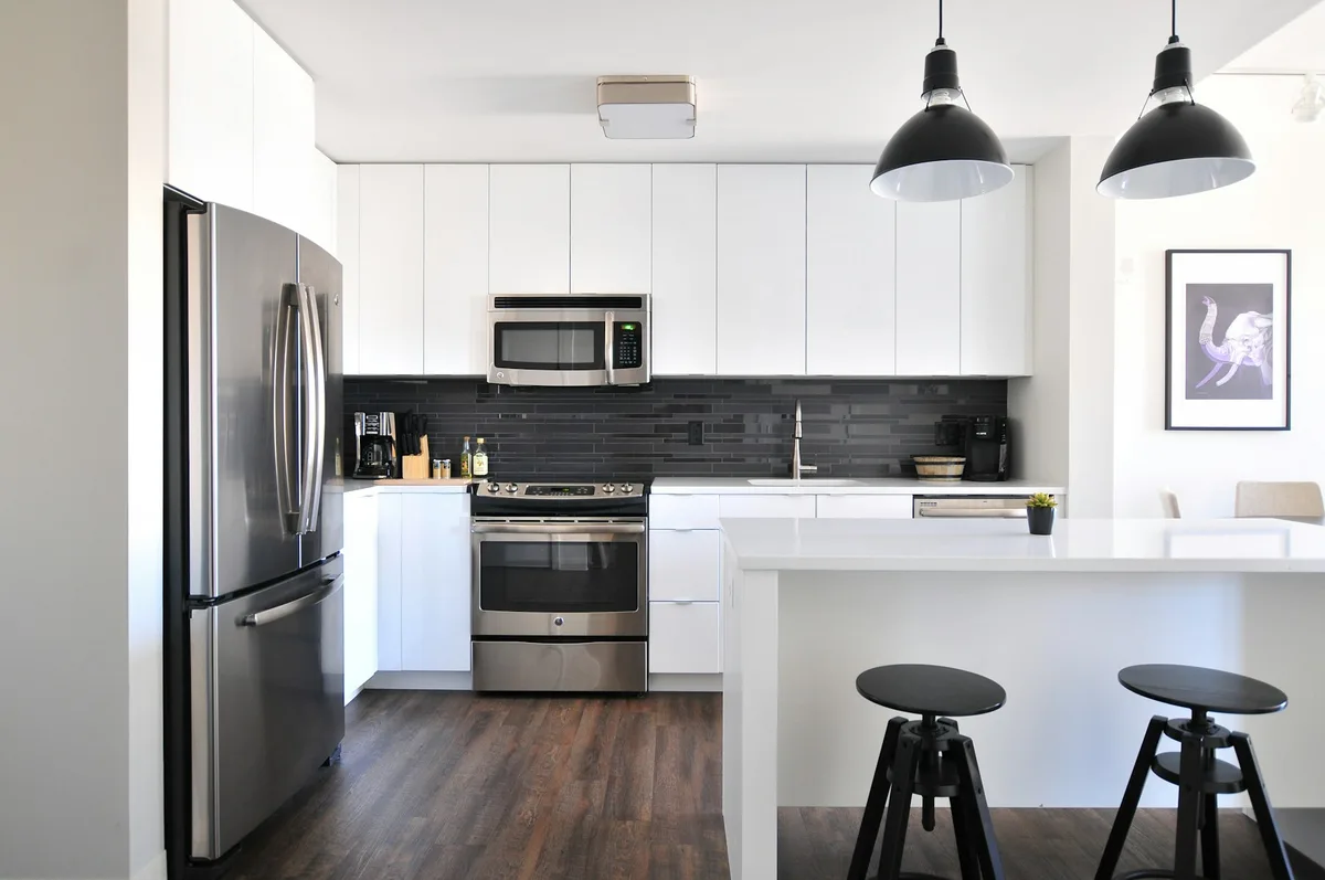 A residential kitchen with cabinets, sink, stove and refrigerator